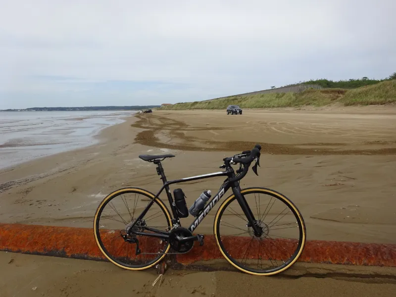 砂浜を走る車と愛車。海と空の境界が広がる風景